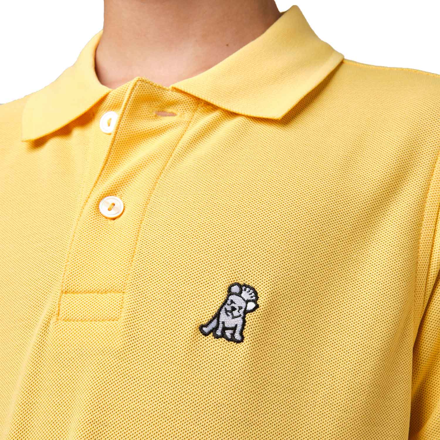 Close-up of the chest area of the yellow polo shirt, featuring the small embroidered logo.