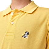 Close-up of the chest area of the yellow polo shirt, featuring the small embroidered logo.