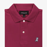 Close-up of the collar area of the burgundy polo shirt, showing the brand label and a small embroidered logo.