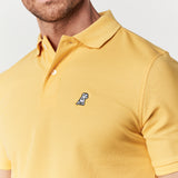 Close-up of the chest area, showing the embroidered logo on the yellow polo shirt.