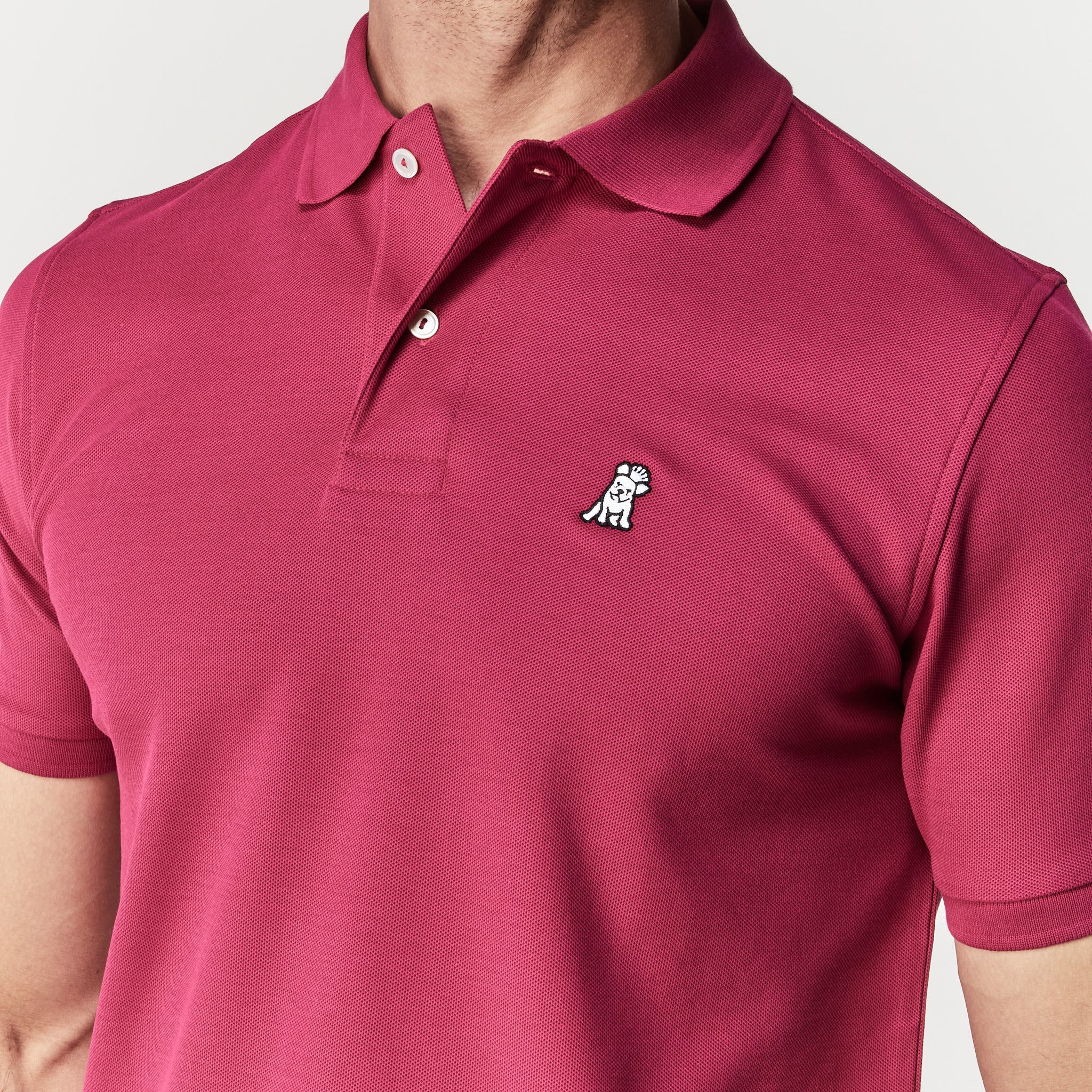 Close-up of the chest area, highlighting the embroidered logo on the burgundy polo shirt.