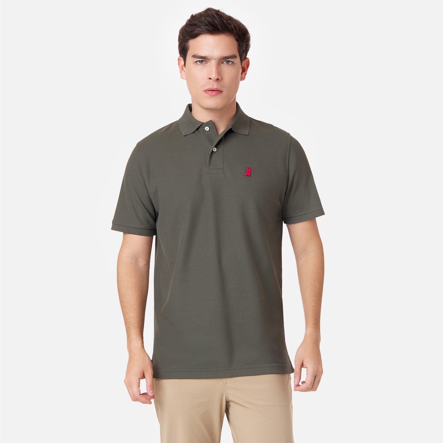 Male model wearing an olive green polo shirt with a red embroidered dog logo and tan pants, standing front view