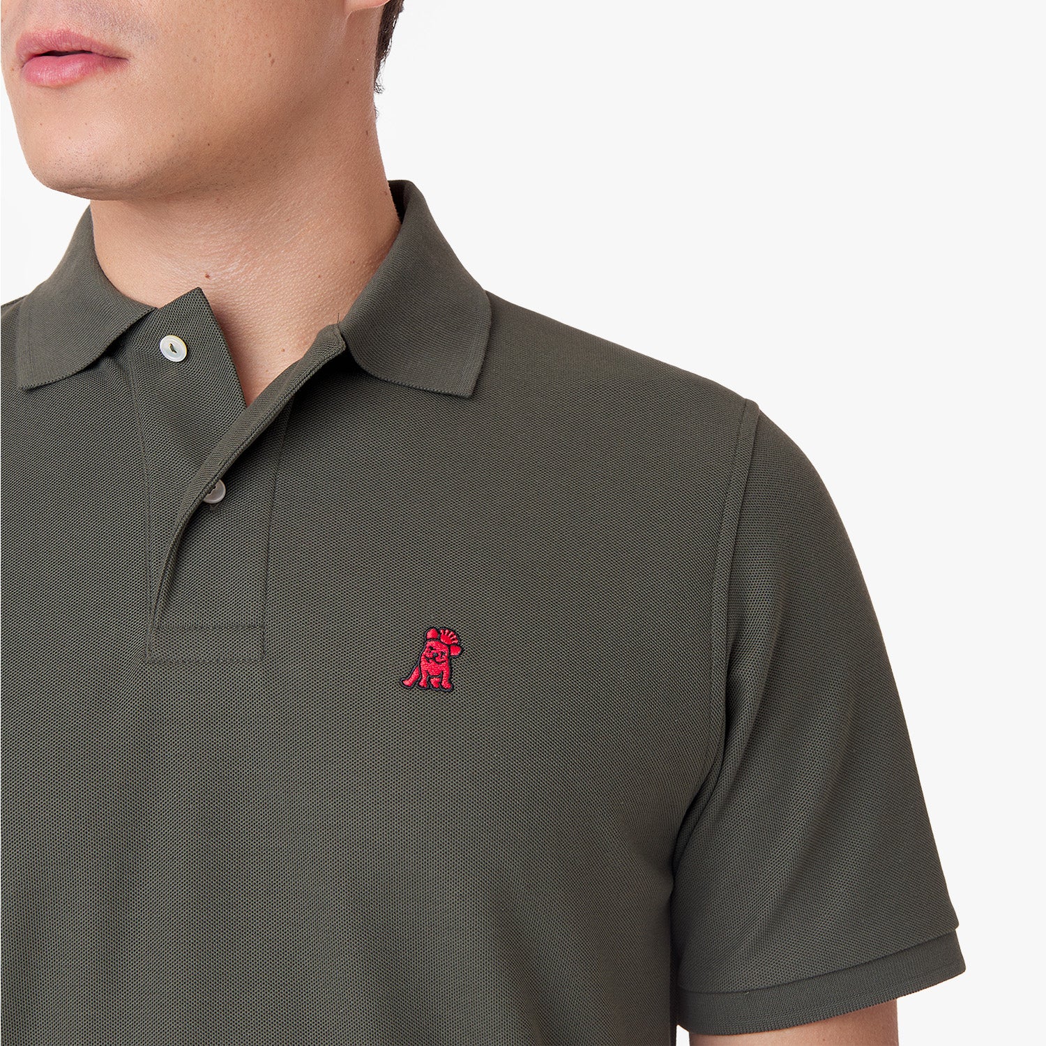 Close-up of an olive green polo shirt showing the collar, buttons, brand tag, and red embroidered dog logo