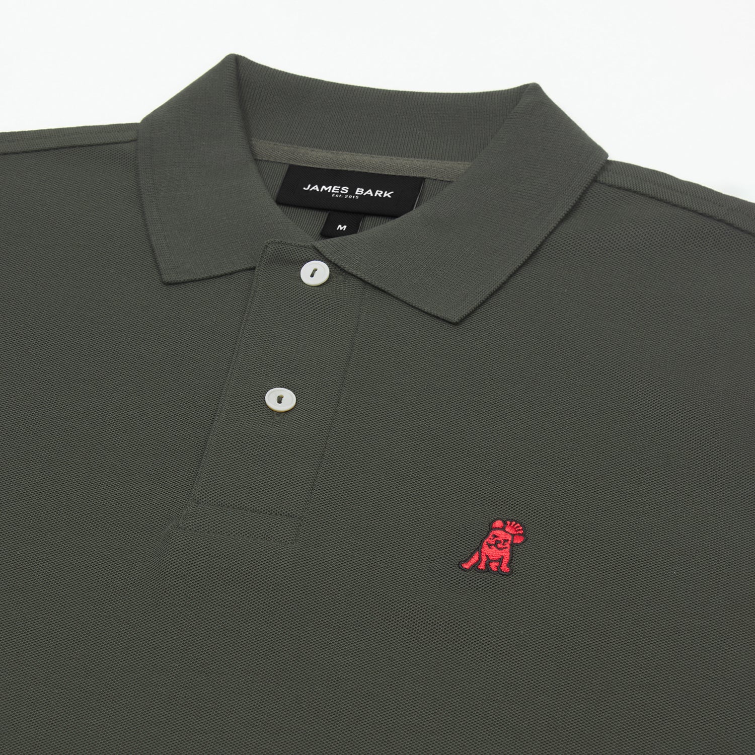 Detailed close-up of the red embroidered dog logo on an olive green polo shirt