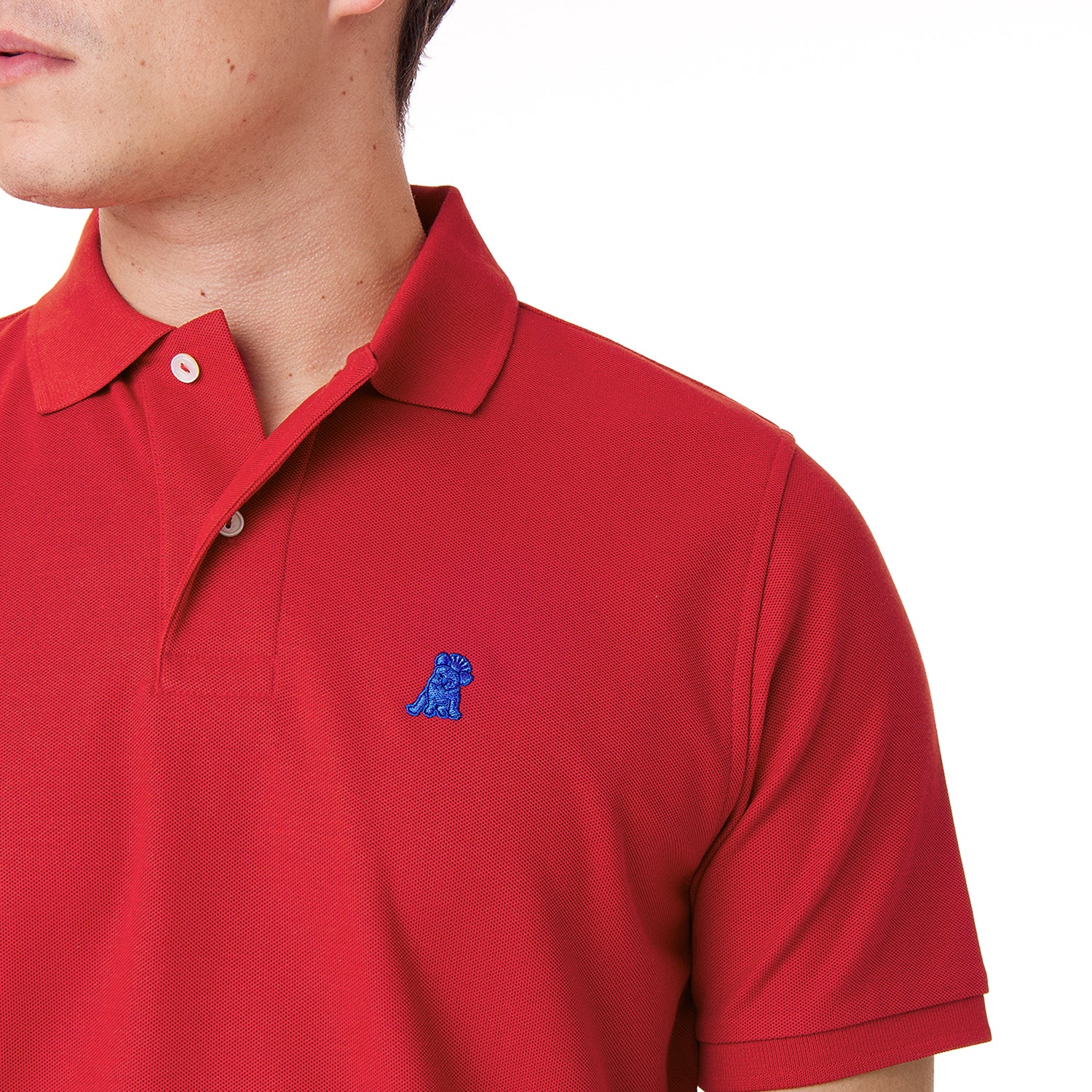 Close-up of a red polo shirt showing the collar, buttons, brand tag, and blue embroidered dog logo