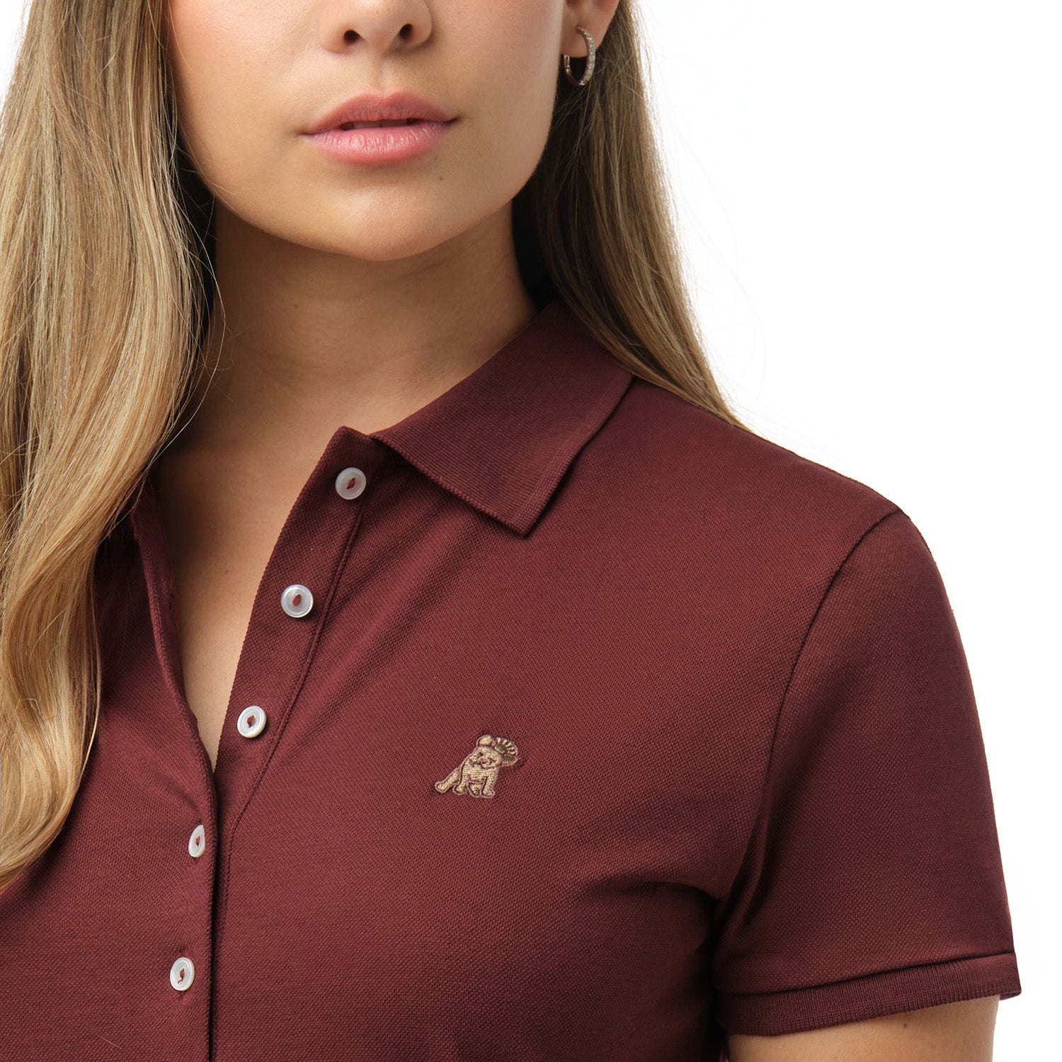 Close-up detail shot of the maroon pique polo shirt collar, white buttons on the placket, and the small embroidered logo on the chest