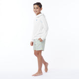 Full body picture of a child wearing a white rashguard and light-colored shorts on a white background