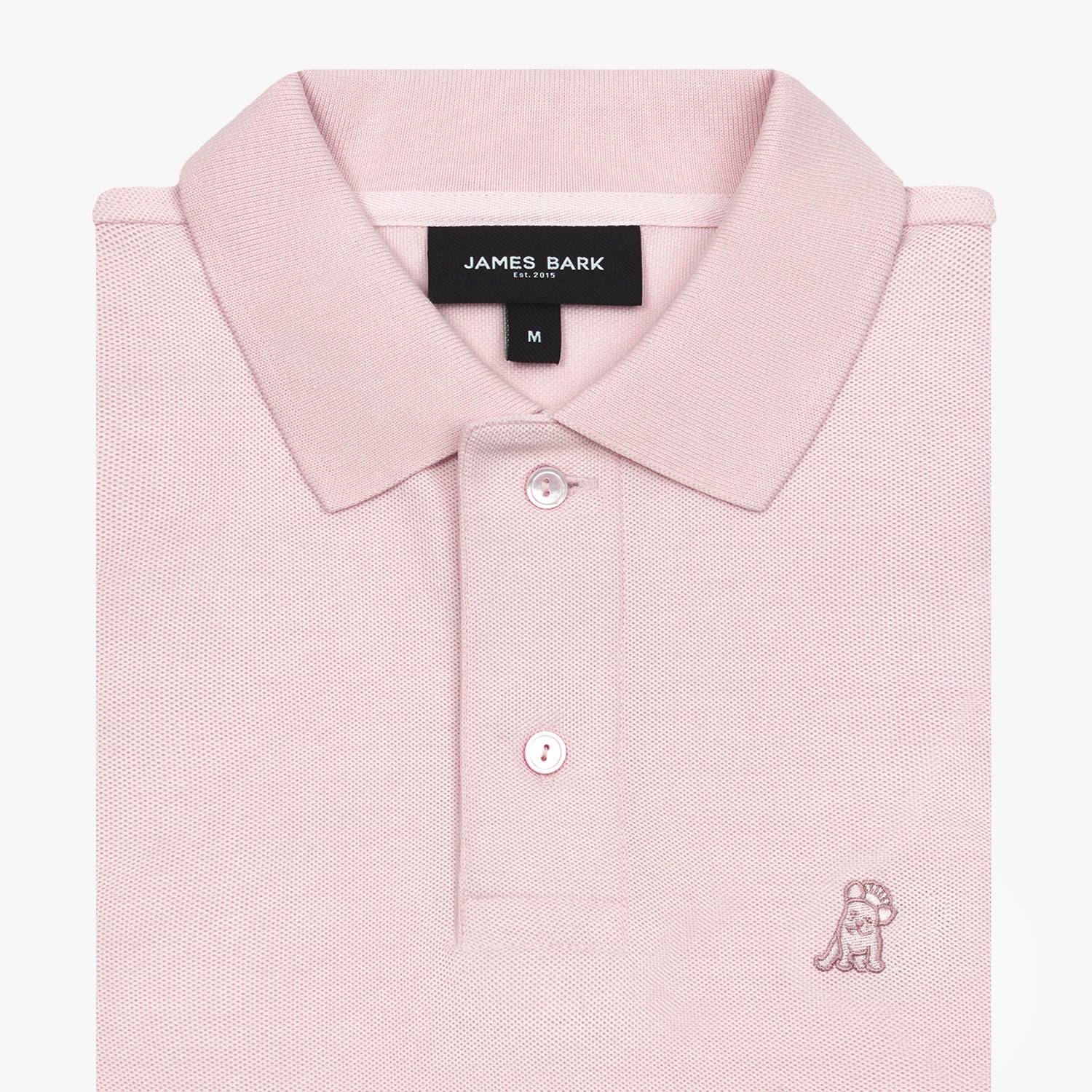 Folded pink polo shirt showing collar, buttons, brand tag, and light pink embroidered dog logo