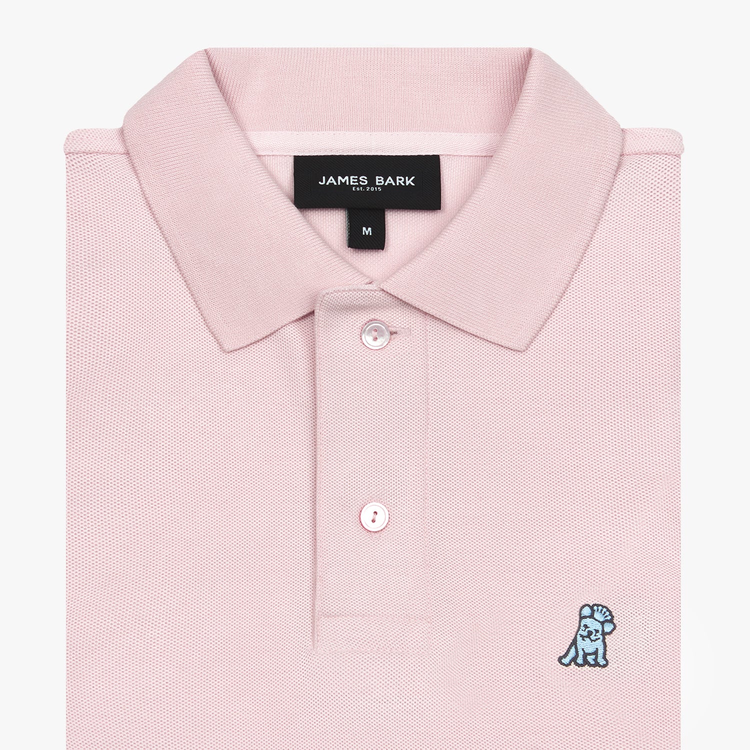 Close-up of a folded pink polo shirt showing the collar, placket with buttons, brand tag, size tag, and embroidered dog logo on the chest