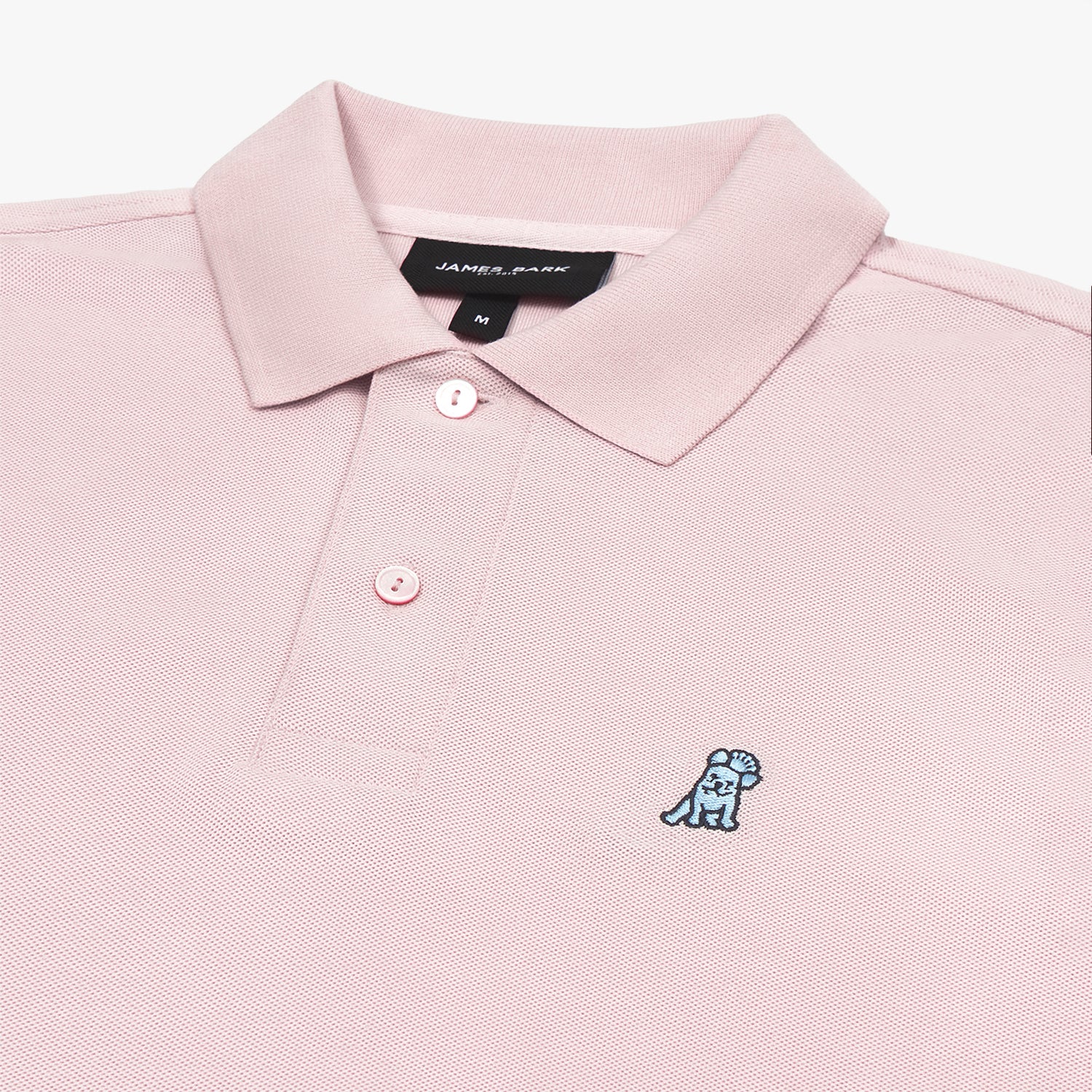 Close-up view of the collar, buttons, brand tag, and embroidered dog logo on a pink polo shirt