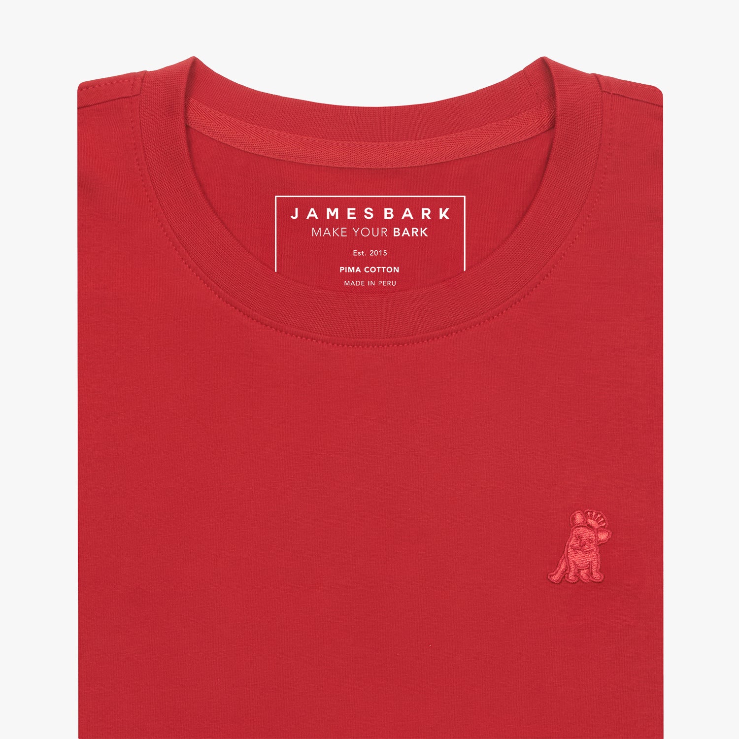 Close-up of the neckline of a red t-shirt, showing the James Bark brand tag, Pima Cotton detail, and a red embroidered dog logo