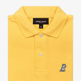 Close-up of the collar area of the yellow polo shirt, featuring the brand label and a small embroidered logo.