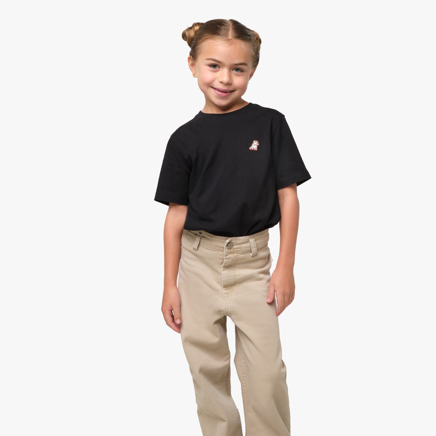 Front view of a boy standing and wearing a black t-shirt with a small embroidered logo on the chest.