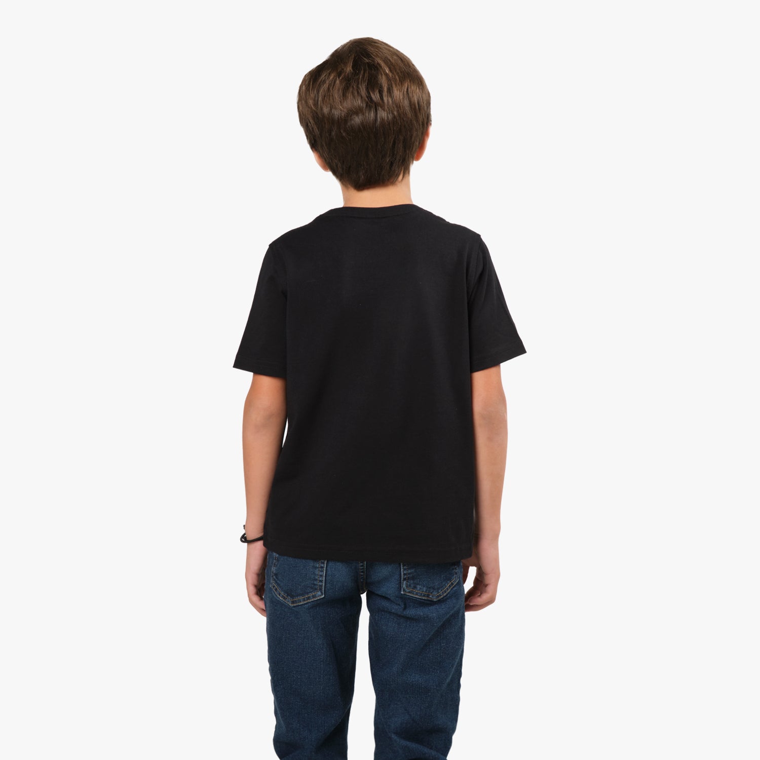 Rear view of the same boy, showing the back of the black T-shirt, which is plain with no design. He is wearing blue jeans.