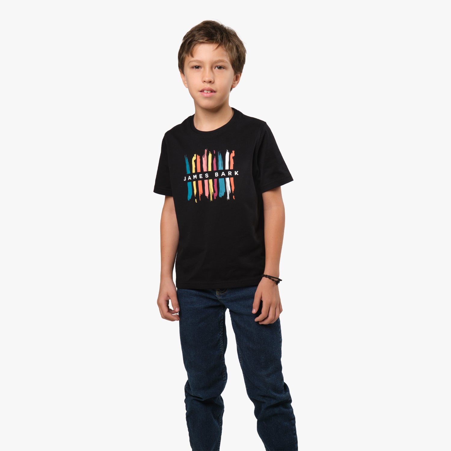 Full-body shot of the young boy, standing and facing forward, wearing the black T-shirt with the colorful pencil design on the front and blue jeans.