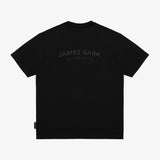 A black short-sleeve T-shirt shown from the back, featuring a subtle dark gray 'JAMES BARK ELEMENTS' logo printed across the upper back