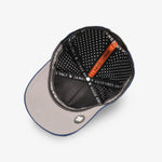 A top-down view of a baseball cap with a light gray brim, black dotted interior panels, and an orange accent strap with white text