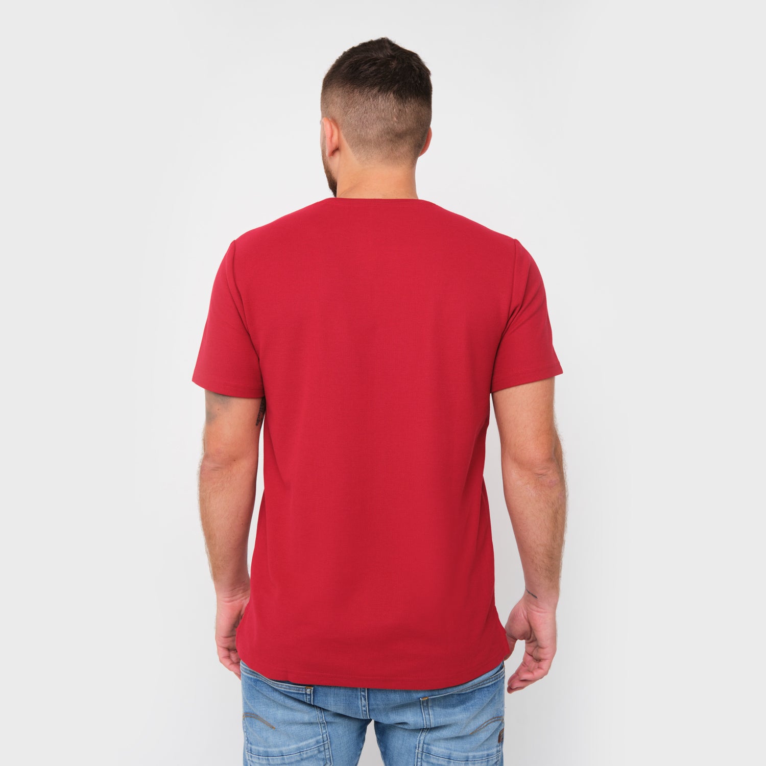 A rear view of a man wearing the red T-shirt and jeans.