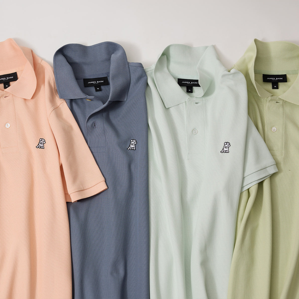 Stack of James Bark polo shirts in pastel colors, each featuring a signature embroidered Frenchie logo.