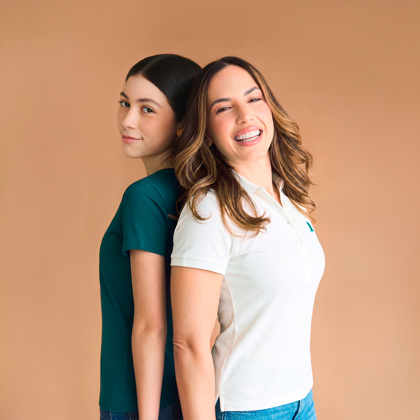 Two women standing back-to-back against a beige background