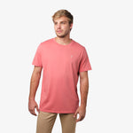 A man wearing a salmon pink t-shirt, standing facing forward with his arms at his sides, paired with light beige pants.