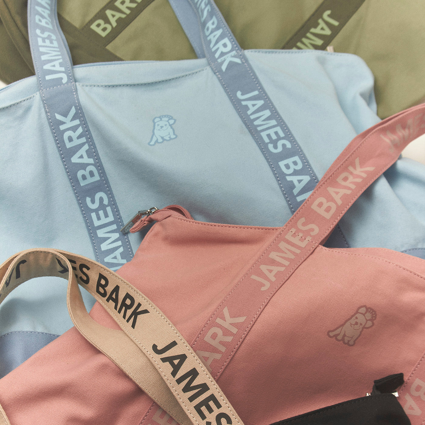 Two bags with 'James Bark' branding on straps against a blurred background.