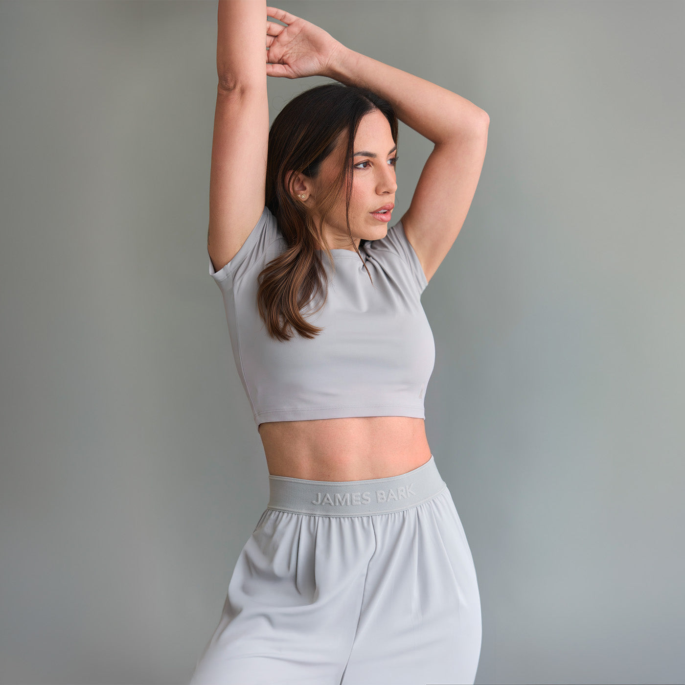 Woman wearing a gray athletic outfit with 'James Bark' branding against a plain background
