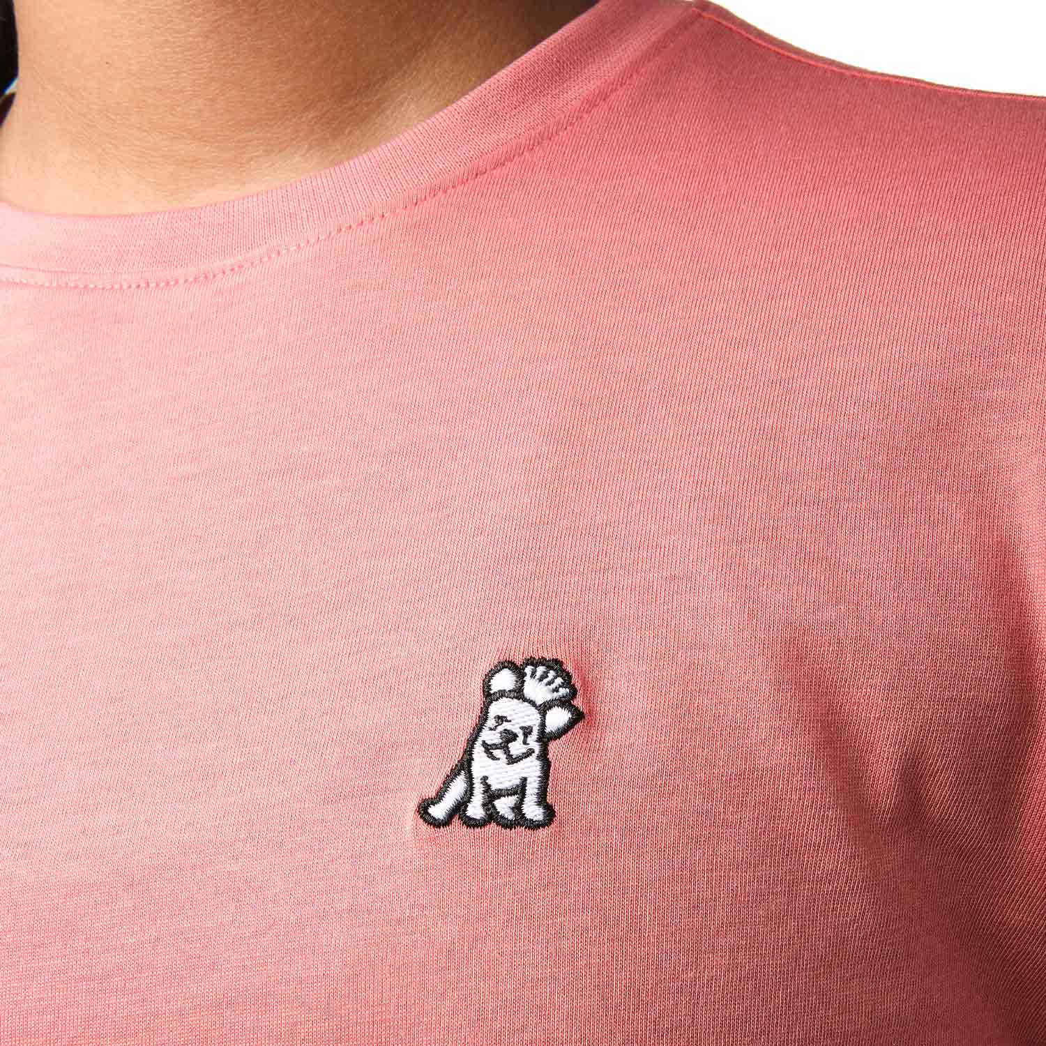 Close-up front view of a girl wearing the pink t-shirt with a small white embroidered logo on the chest.