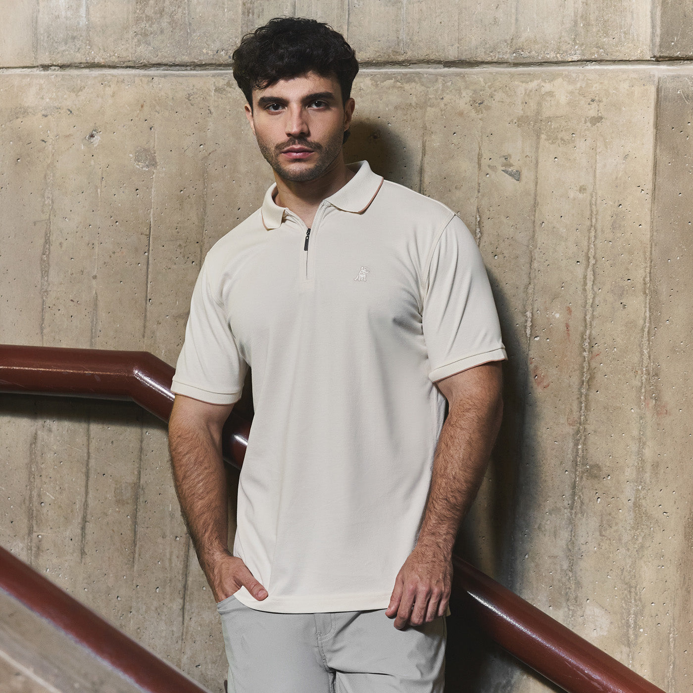 Man wearing a cream-colored James Bark short-sleeve polo with a quarter-zip collar and small embroidered Frenchie logo.