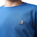 Close-up front view of a boy wearing the blue t-shirt with a small white embroidered logo on the chest.