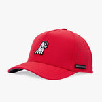 A red structured baseball cap with a curved brim, featuring a black-and-white embroidered dog patch on the front and a black brand label on the side. 