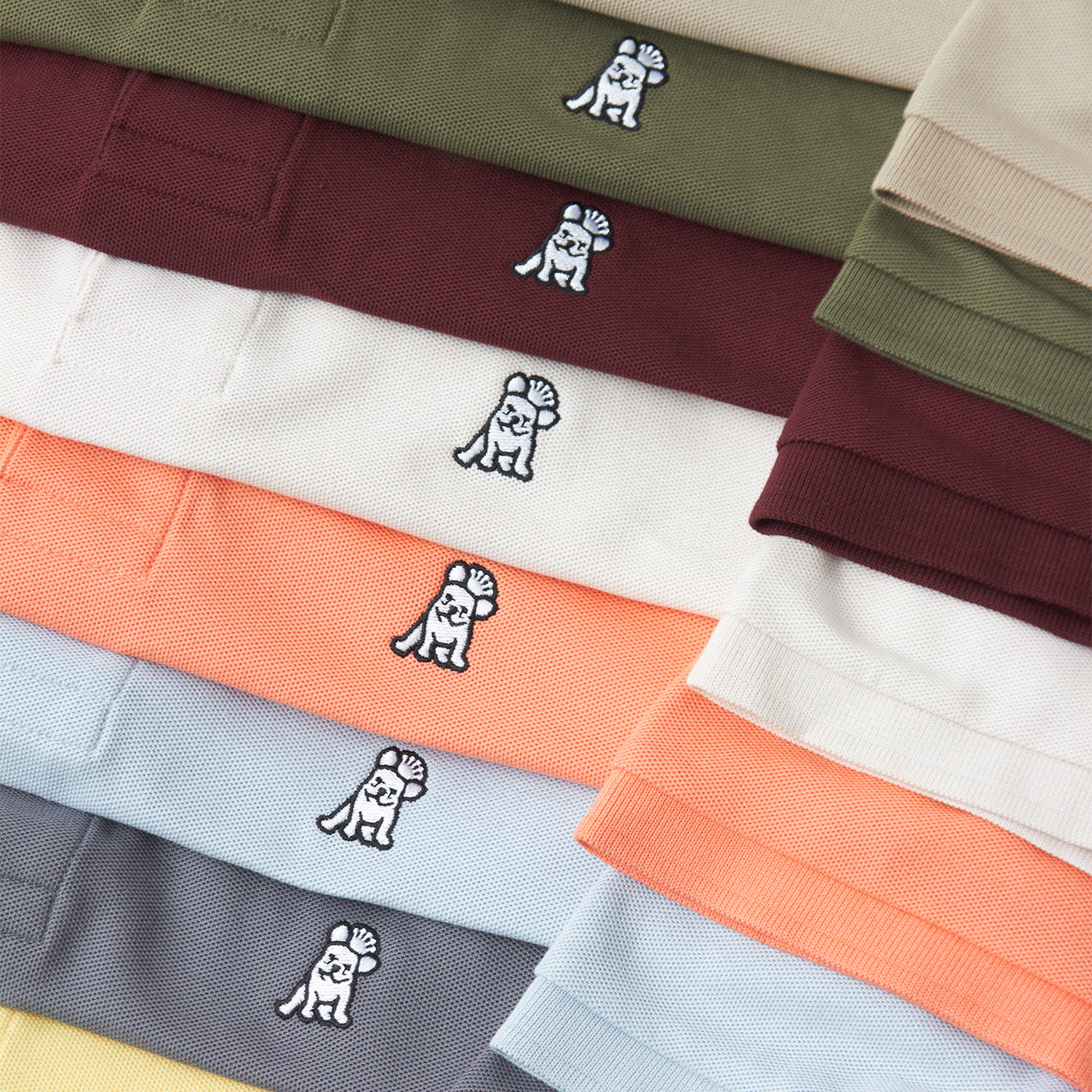 Stack of folded polo shirts in various colors with a small logo on each shirt.