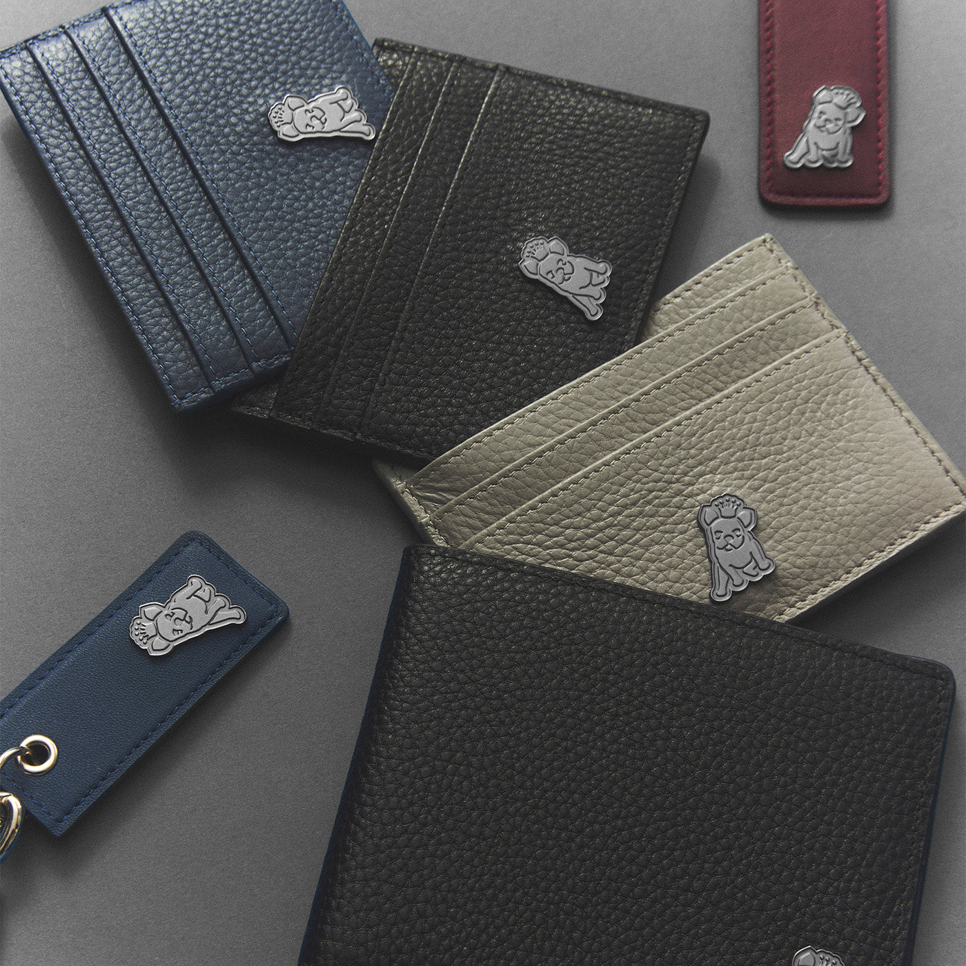 Collection of leather card holders and keychains with a brand logo on a gray background