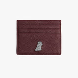 A front view of a deep red leather cardholder with a pebbled texture. The design features a small silver embossed dog logo at the bottom, along with multiple card slots for added utility.