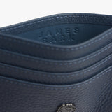 Close-up view of a blue textured leather cardholder with the embossed text 'JAMES BARK' on the inside. The stitching and grain detail of the leather are prominently visible.