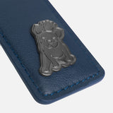 A close-up view of a blue leather tag adorned with a metallic emblem of a dog wearing a crown, complemented by matching blue stitching.