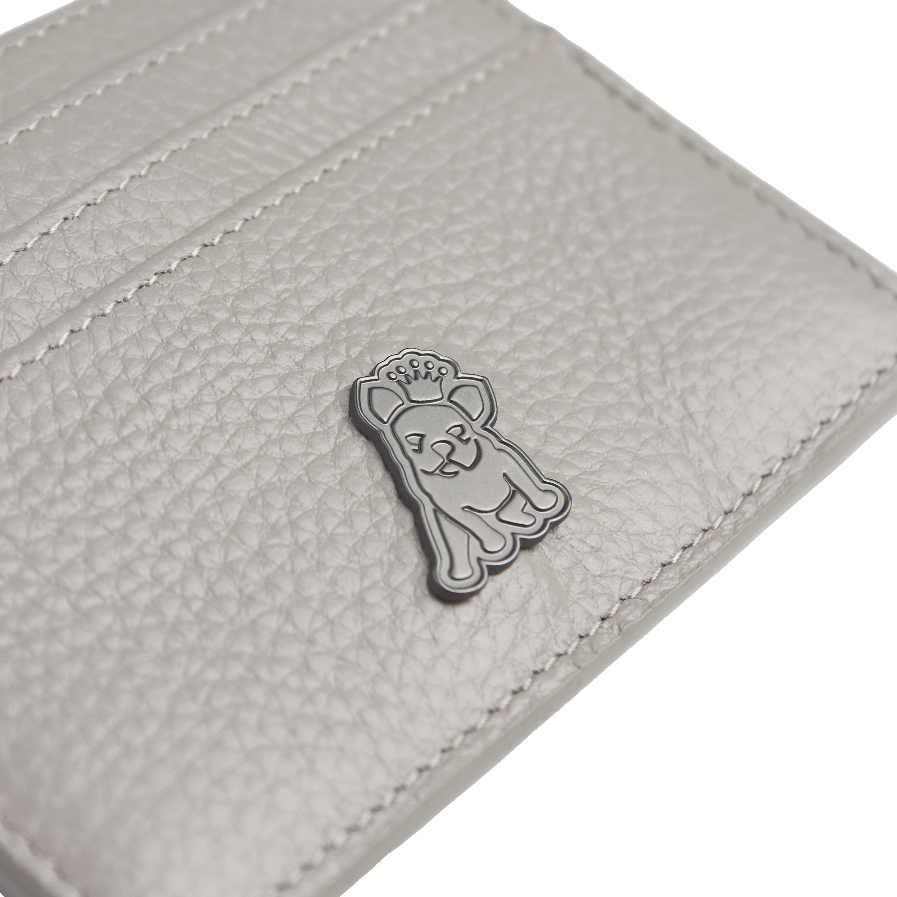 Close-up view of a gray textured leather cardholder featuring a small metallic emblem of a dog with a crown, adding a unique branding element to the accessory.