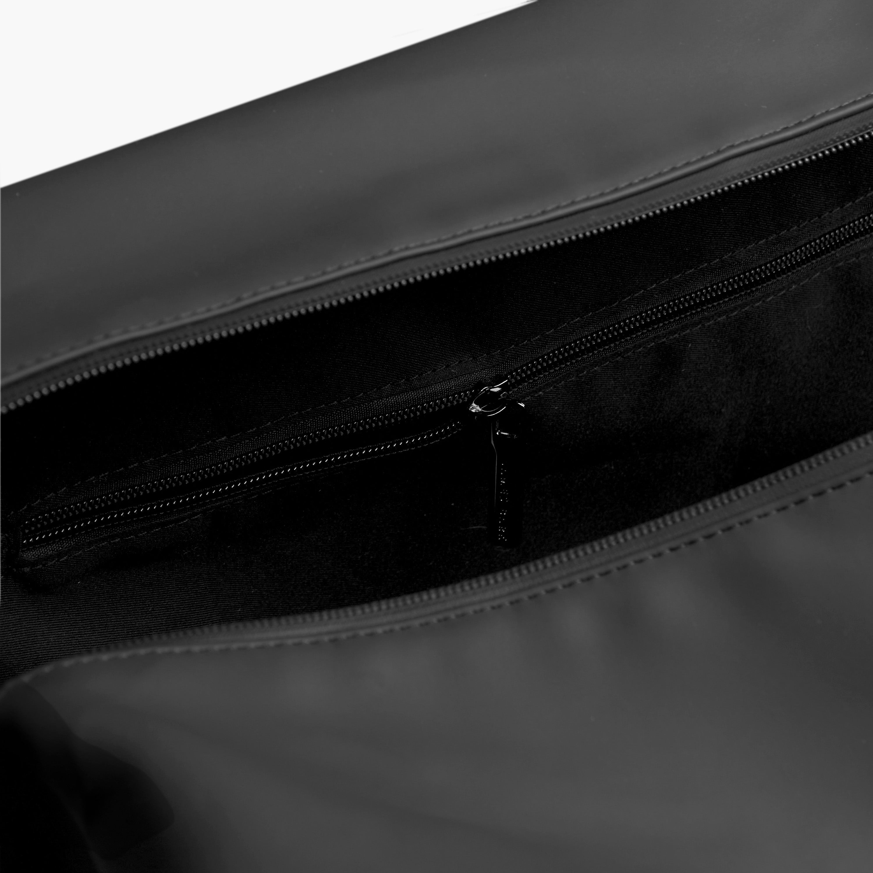 A partial view of the bag’s interior, showing the lining and an additional zipper pocket.