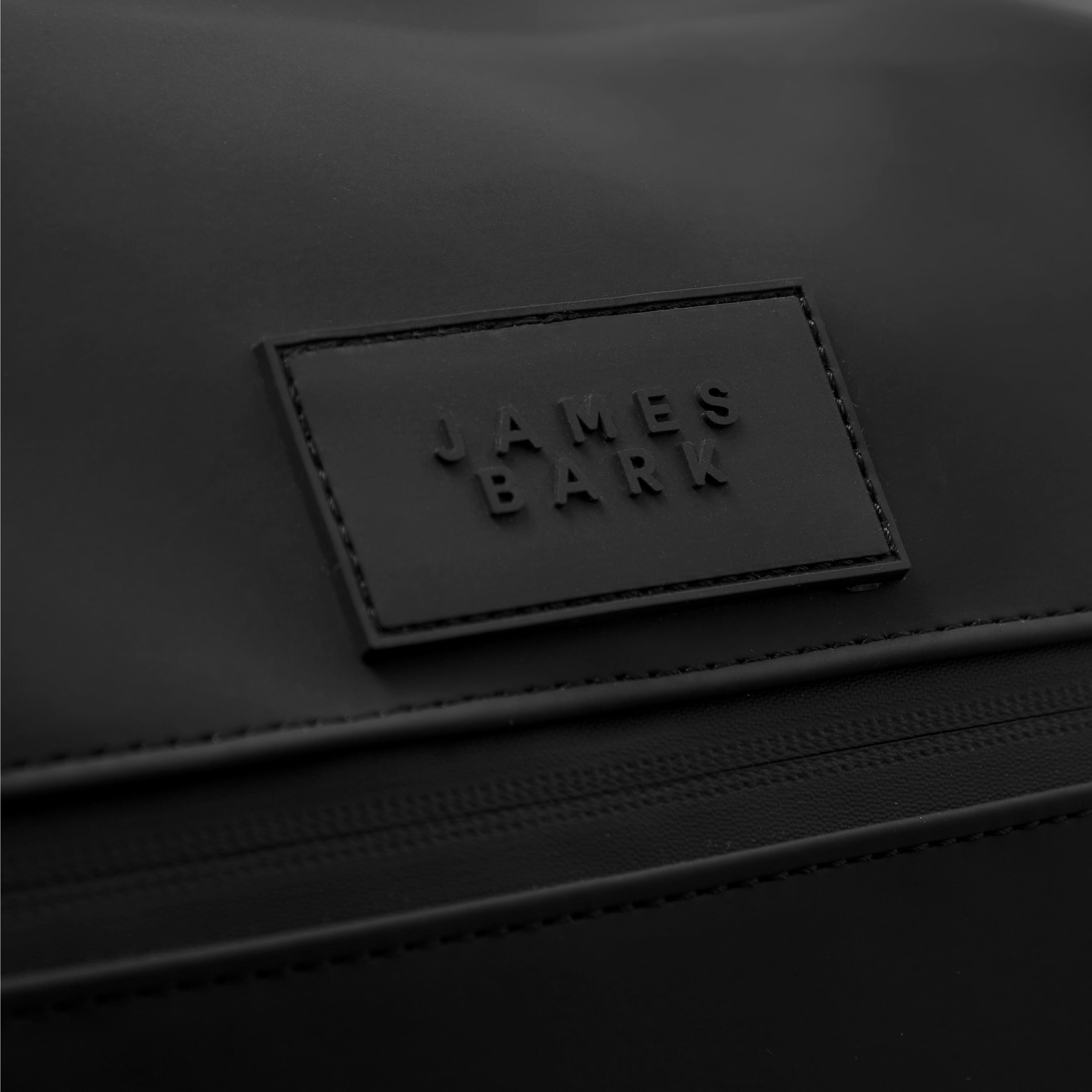 A close-up of the front brand patch, showing the embossed "James Bark" logo on a rectangular black leather-like material.