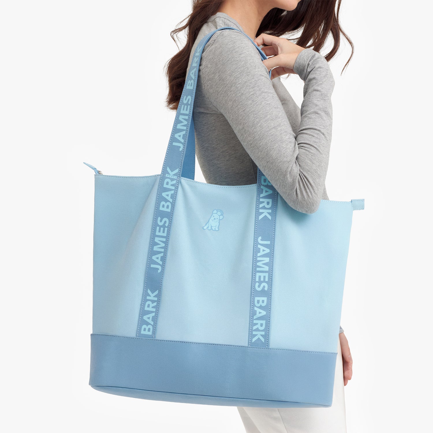 Person holding a light blue tote bag with 'James Bark' branding.