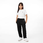 Young model wearing black jogger pants paired with a white T-shirt, hands in pockets, styled with white sneakers