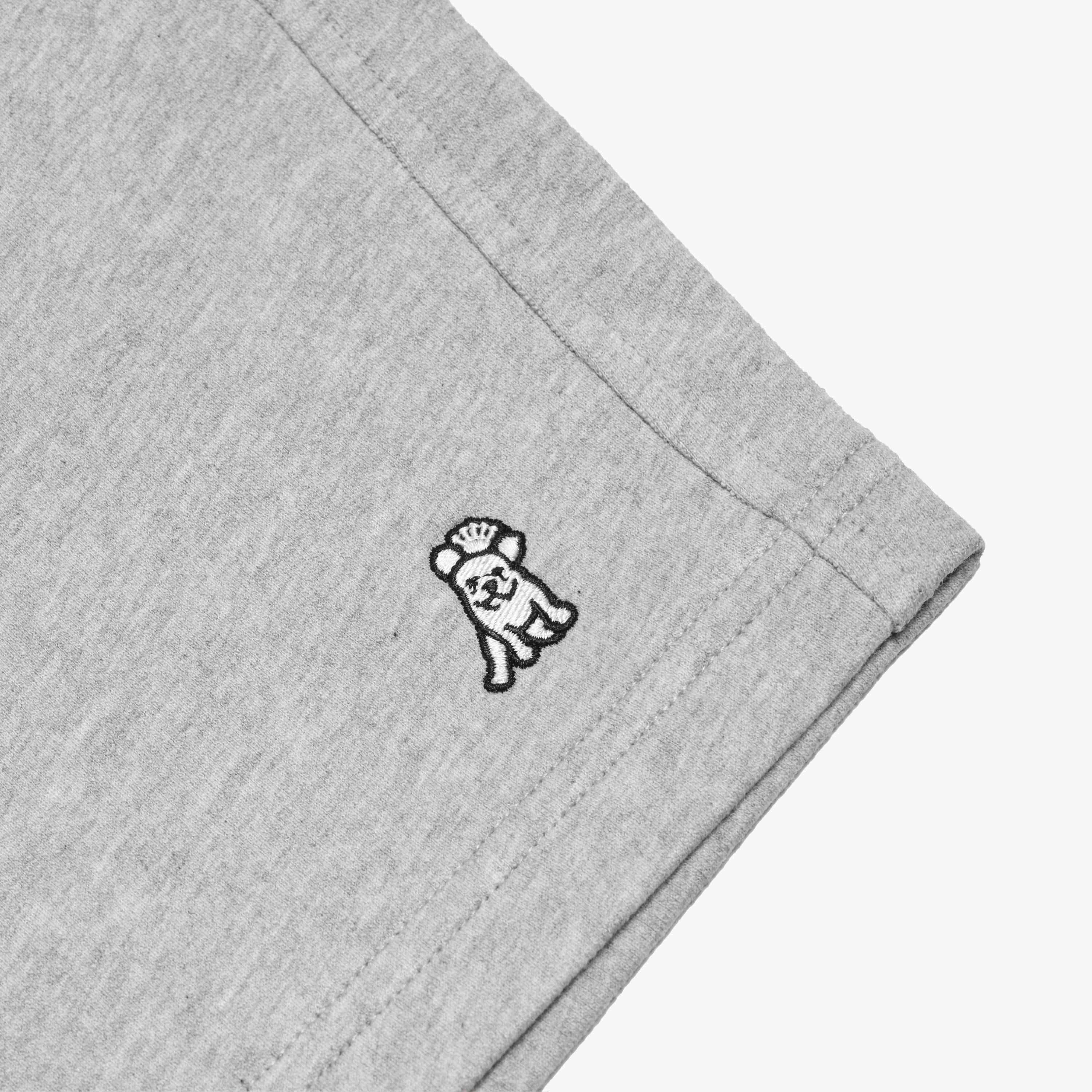 Flat-lay close-up of the embroidered dog logo on the gray shorts, showcasing the detailed stitching and fabric texture.