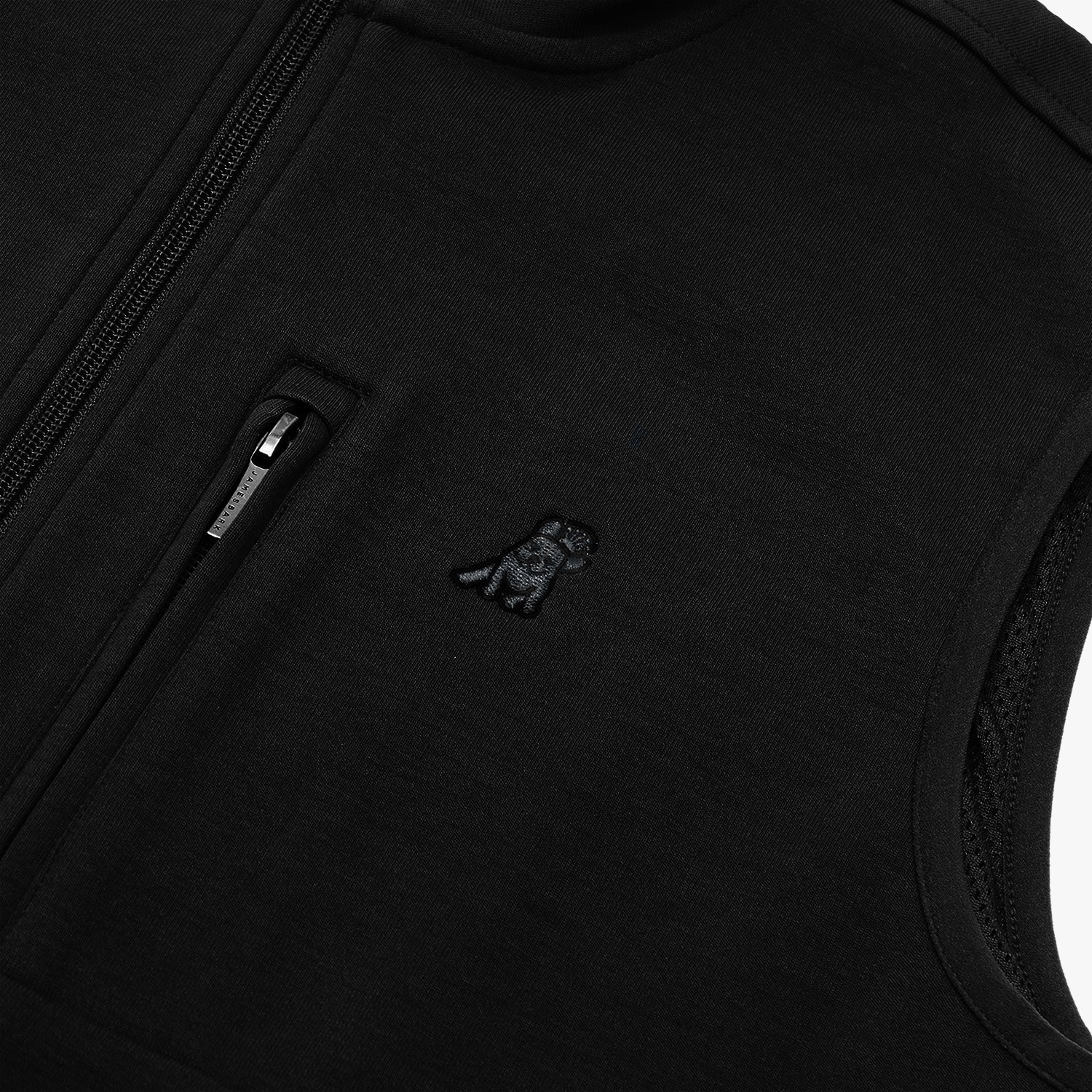  A close-up shot of a zippered pocket on the jacket, showing the small, minimalistic brand logo.