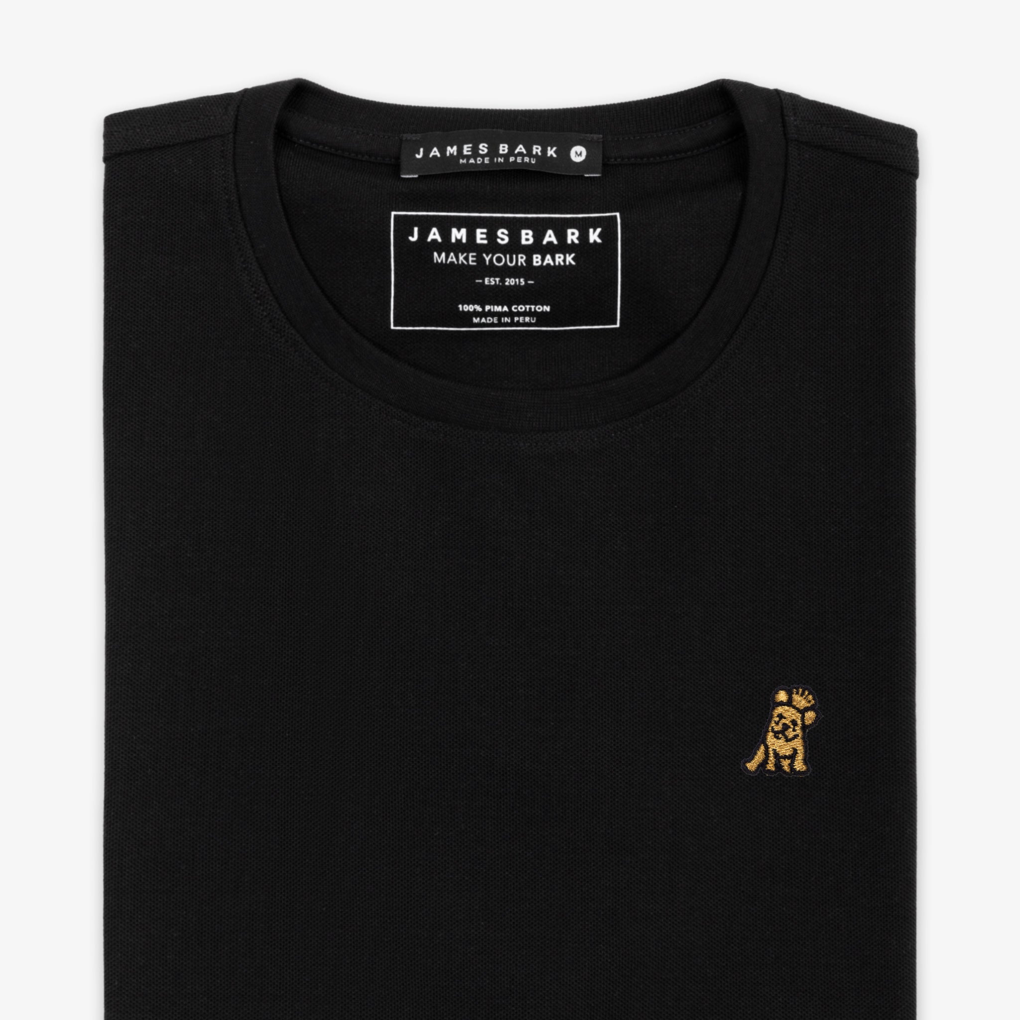 Close-up of the neckline of a black T-shirt, showing the small golden embroidered logo on the chest.