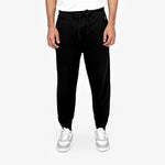 Front view of a person wearing black jogger-style sweatpants with a drawstring waist, paired with white sneakers featuring gray accents. The person is also wearing a white T-shirt, and the background is plain white." Let me know if any changes are needed