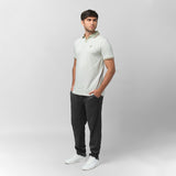 A full-body view of a man wearing the dark gray pants paired with a light gray or off-white polo shirt and white shoes, presenting a stylish, casual look.