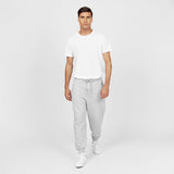 Full-body image of a man wearing a plain white T-shirt paired with light gray jogger-style sweatpants featuring a drawstring waist and cuffed ankles. The man is also wearing white sneakers and standing in a relaxed pose against a plain white background." Let me know if you'd like any edits