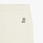 Close-up of the embroidered dog logo on the cream-colored jogger pants, near the waistband, showcasing detailed stitching