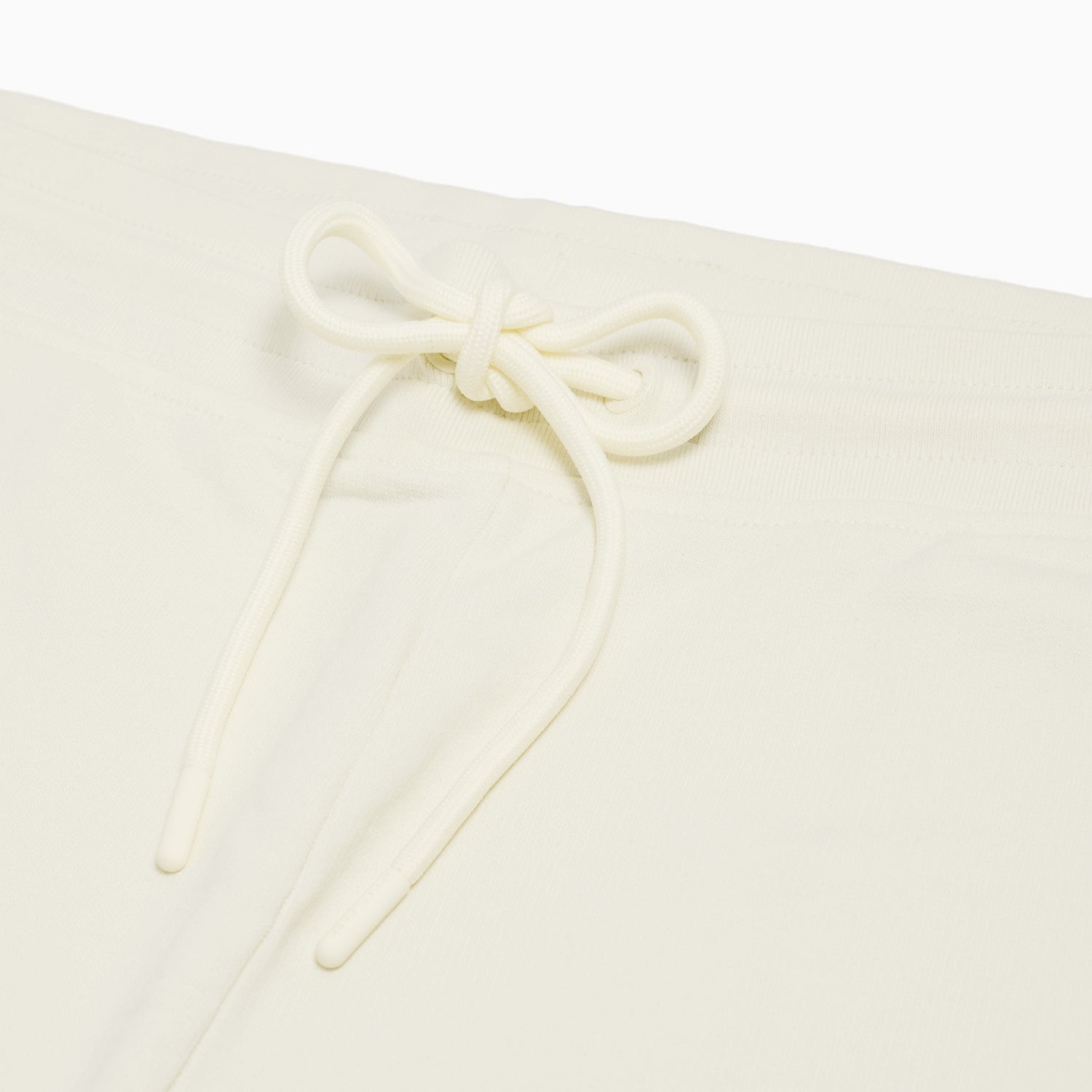 Close-up of the drawstring waistband on the cream-colored jogger pants, emphasizing the adjustable fit