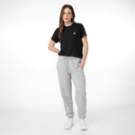 The image shows a woman standing in a casual outfit, consisting of a black t-shirt and light gray jogger pants. She has white sneakers on and her hair is long, straight, and dark. The look appears comfortable and sporty. The background is neutral, enhancing the simplicity of the outfit. Let me know if you'd like to add more details or adjustments